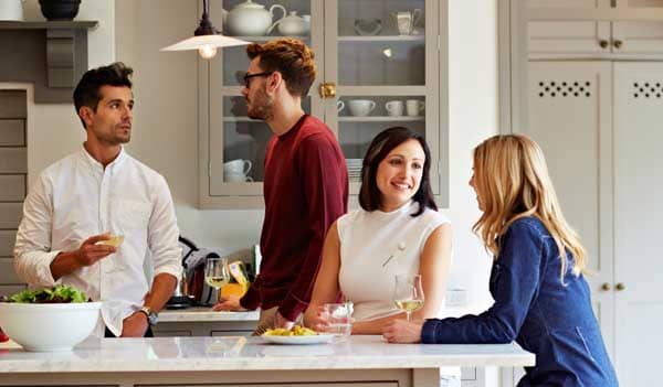 Four friends drinking in a kitchen